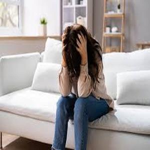 A person sitting on a couch with their head in their hands, appearing distressed or overwhelmed, symbolizing anxiety or intrusive thoughts.